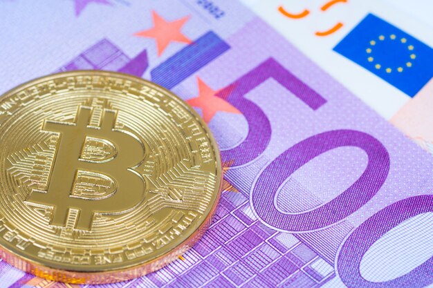 Golden bitcoin over euro banknotes close up