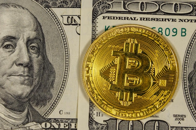 Golden bitcoin on hundred dollar bills background