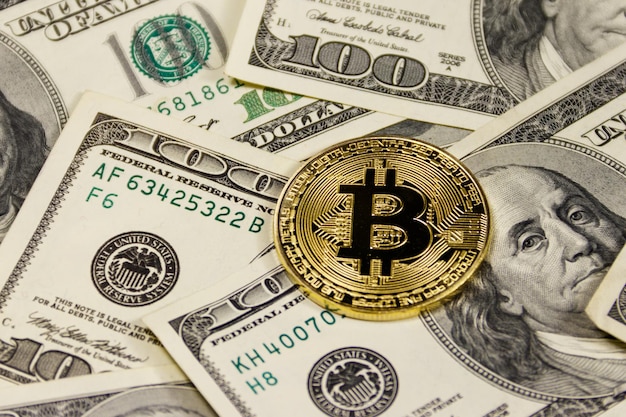 Golden bitcoin on hundred dollar bills background