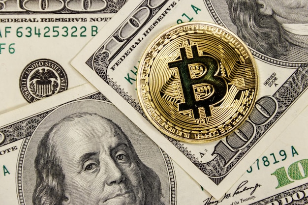 Golden bitcoin on hundred dollar bills background