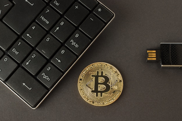 Bitcoin dorato, tastiera e chiavetta su una vista superiore del fondo scuro