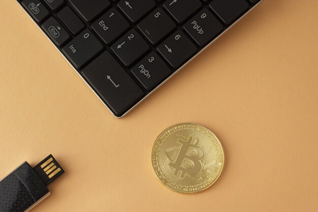 Foto vista dall'alto di bitcoin dorato, tastiera e flash drive