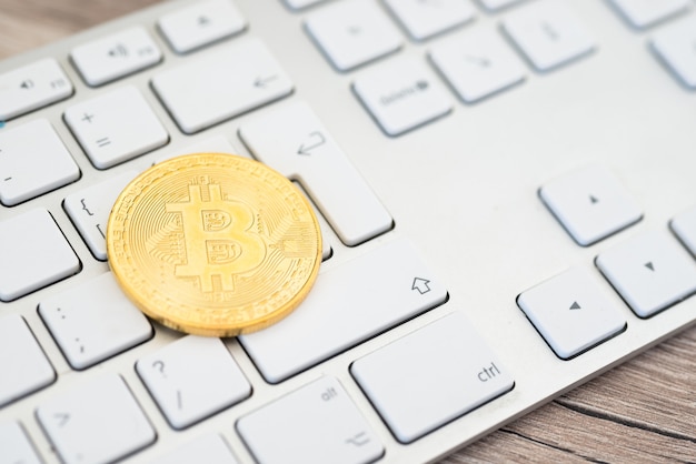 Golden bitcoin lying on a white keyboard