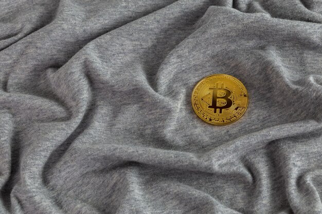 Brillante bitcoin dorato su panno di cotone stropicciato grigio