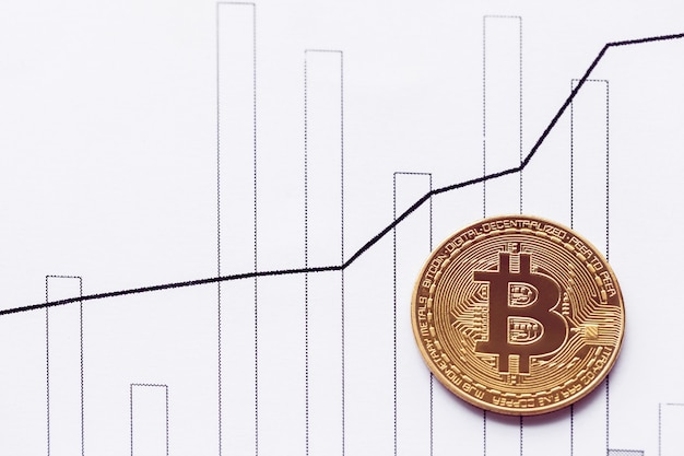 Golden bitcoin on the table of a rising chart