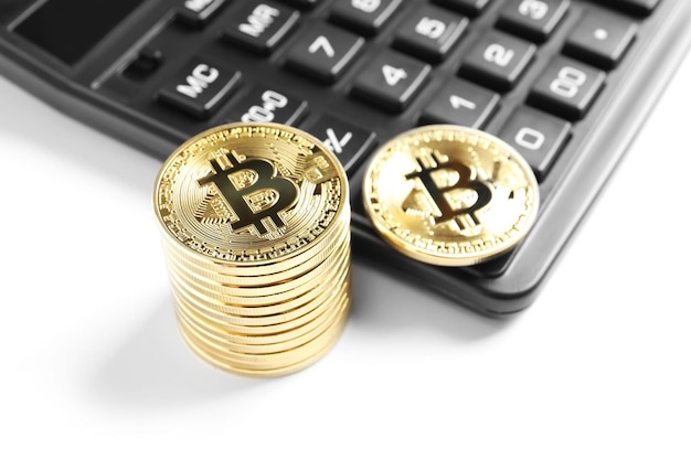 Golden bitcoins with calculator on white background