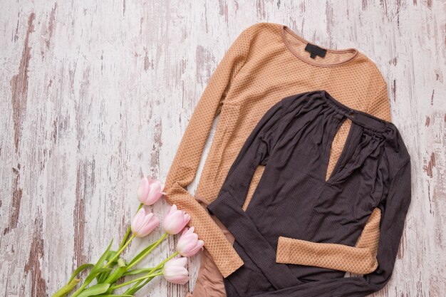 Golden and black blouse, pink tulips on a wooden background