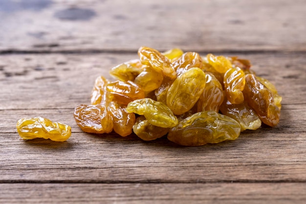 Golden and black raisins on wooden table background.