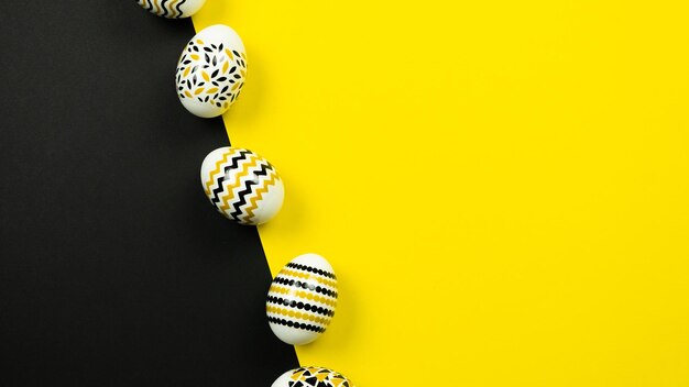 Golden black white eggs with a geometric pattern on a yellow and black background View from above Easter card with copy space for text Webbanner