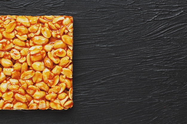 Golden boletus kozinaki from roasted peanut beans energy bars. Black textural background, top view