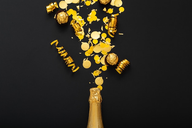 Golden bottle of champagne spills out gold sparkles.