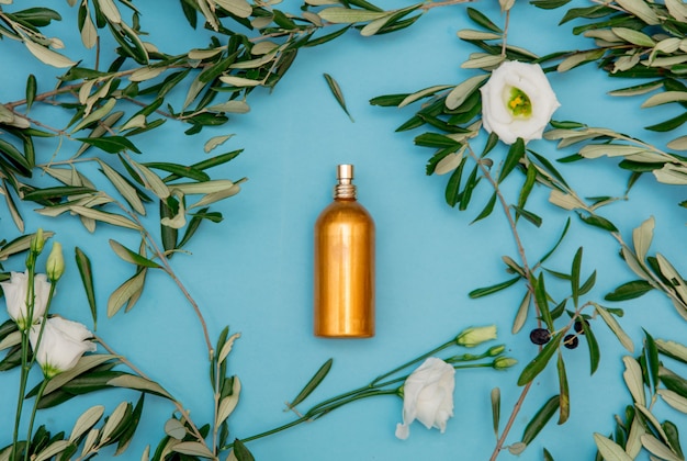 Golden bottle with olive branches on blue background.