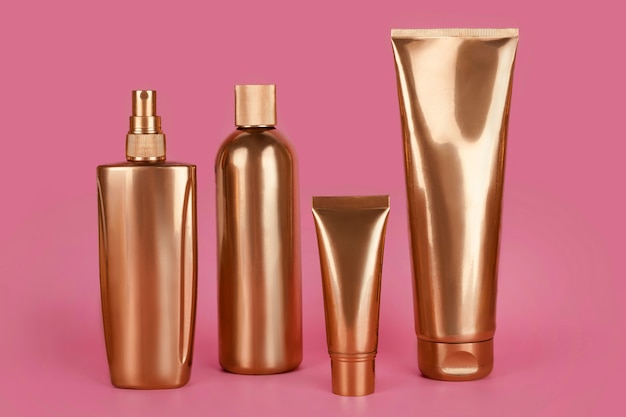 写真 金色のボトル、ピンクの表面に化粧品
