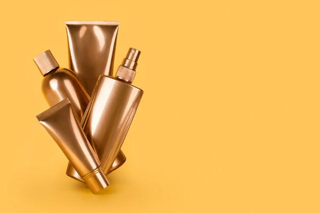 Golden bottles, cosmetic products on yellow surface