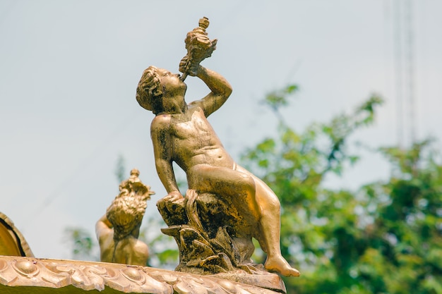 Statua dorata del ragazzo sulla fontana nel parco