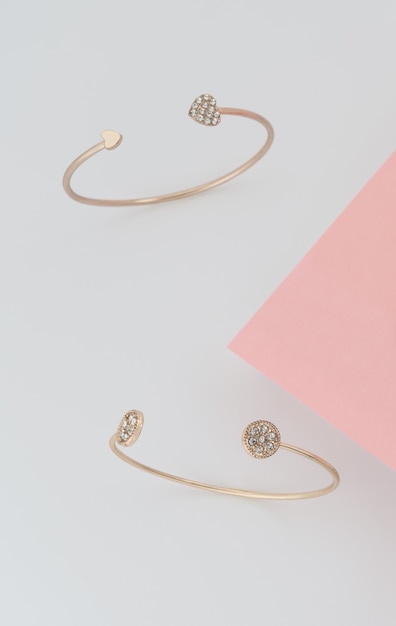 Golden bracelets with brilliants on pink and white background