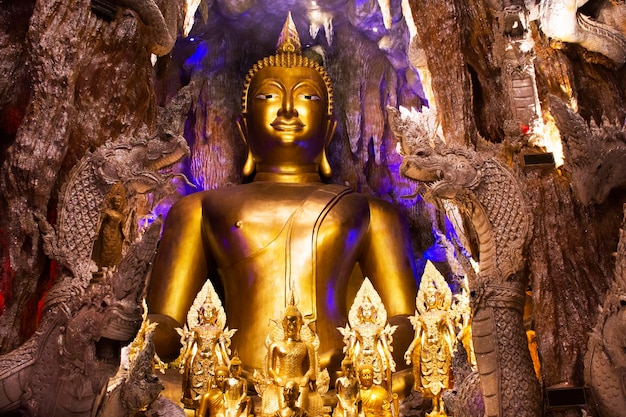 Statua dorata dell'immagine del buddha e guardiano naga di wat maniwong per i thailandesi viaggio visita tunnel grotta e rispetto pregando benedizione santo culto mistico al tempio mani wong a nakhon nayok thailandia