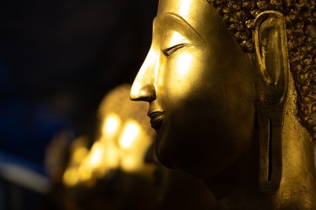 Золотая статуя Будды в свете и тени солнца в храме Ват Пра Шри Махатхат.