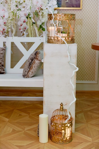 白い木製の台座の上のキャンドルと黄金のケージ結婚式の写真ゾーン