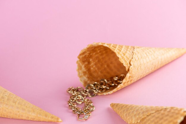 Golden chain with a heart in waffle cone on pink background beauty glamour love fashion concept