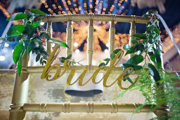 Golden chairs with sign bride and groom with green ruscus twigs\
event hall with golden decorations and tropic palm leaves