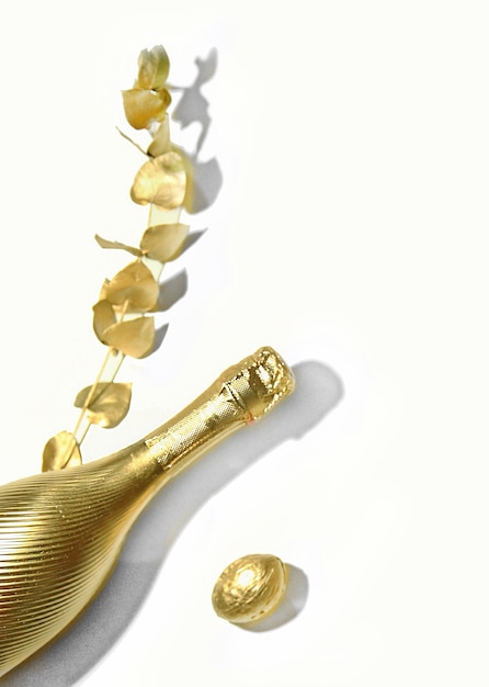 Фото Золотая бутылка шампанского с золотой веткой и золотым орехом концепция праздничной вечеринки