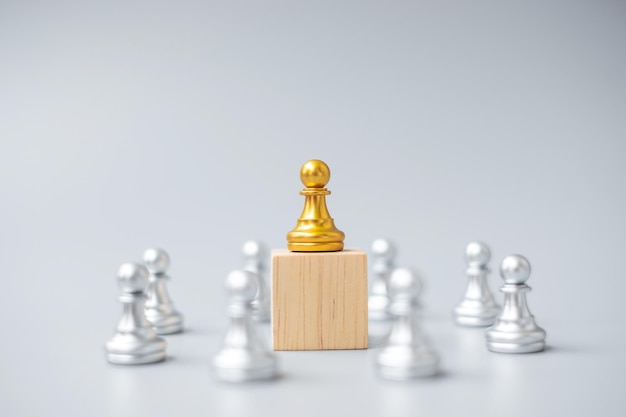Golden chess pawn pieces or leader businessman with circle of\
silver men victory leadership business success team and teamwork\
concept