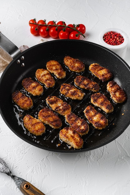 Golden chicken nuggets frying in hot oil set on white stone table background