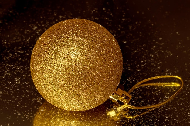 A golden Christmas ball on a dark background Closeup A symbol of Christmas and New Year