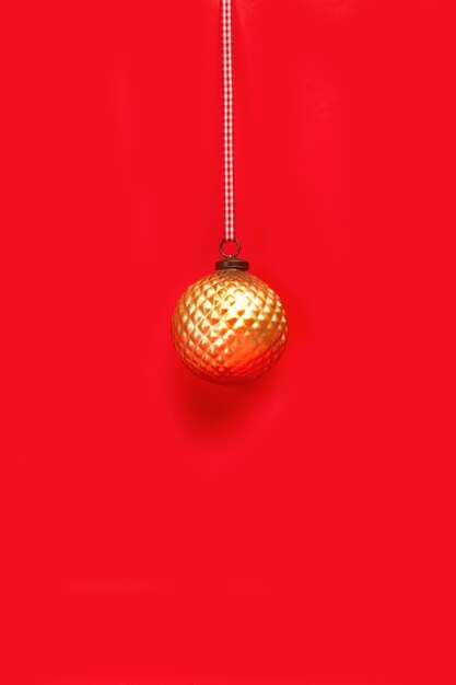 Golden christmas ball ornament on a red background with copy space