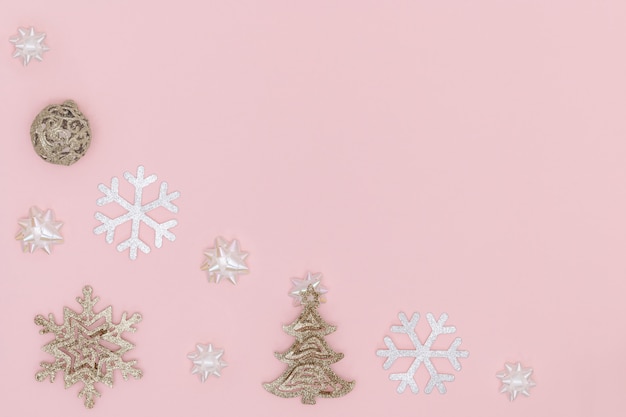 Golden christmas ball, snowflake, chrismas tree, gift bows on pastel pink background