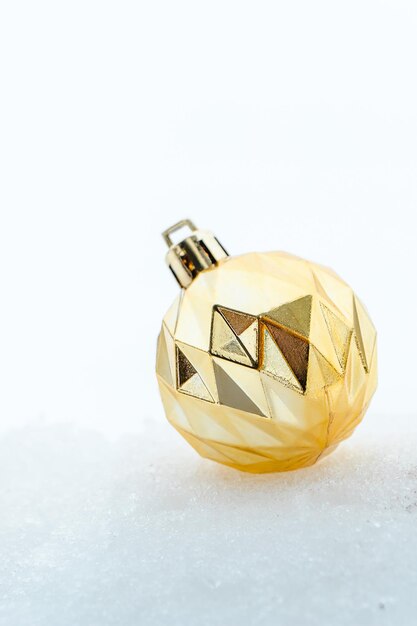 Golden Christmas ball on white snow. Christmas and New Year symbol. Design for greeting card. Festive background, copy space.