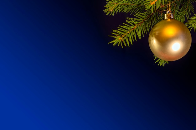 Golden Christmas balls hang on a Christmas tree on a blue background..