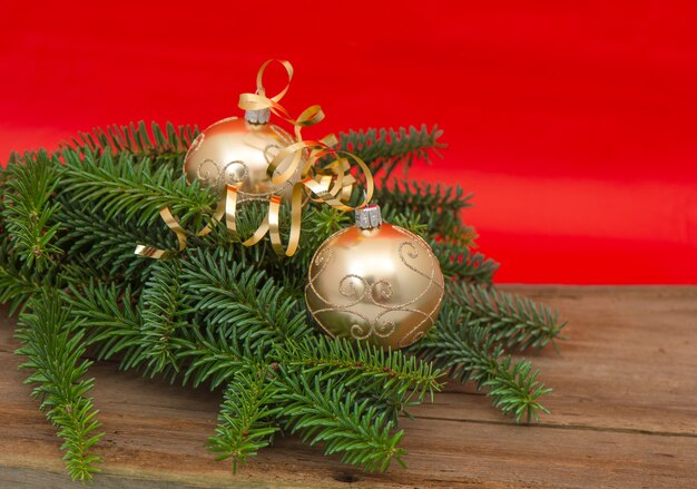 Golden christmas balls with christmas tree branch on red background