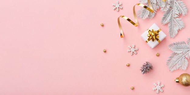 Decorazione dorata di natale su fondo rosa con lo spazio della copia