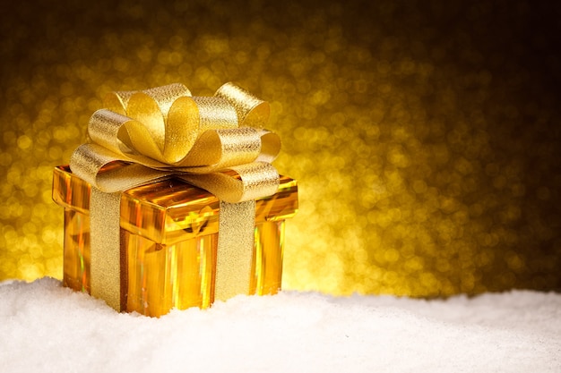 Golden Christmas gift in snow