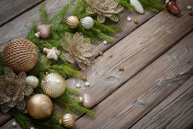 Golden christmas toys with fir branches on dark wooden background