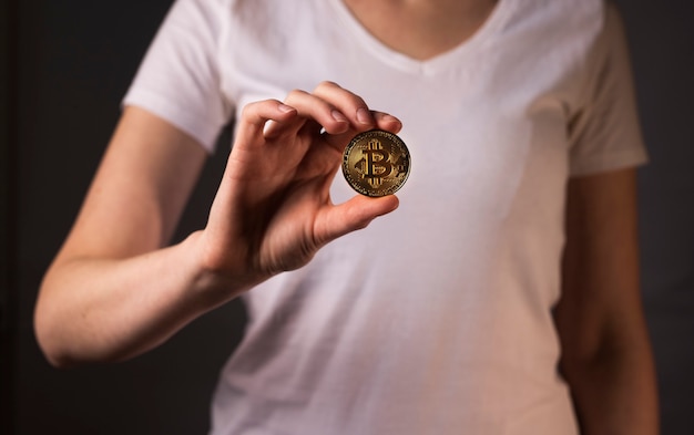 Golden coin of BTC or bitcoin held bu female hand.