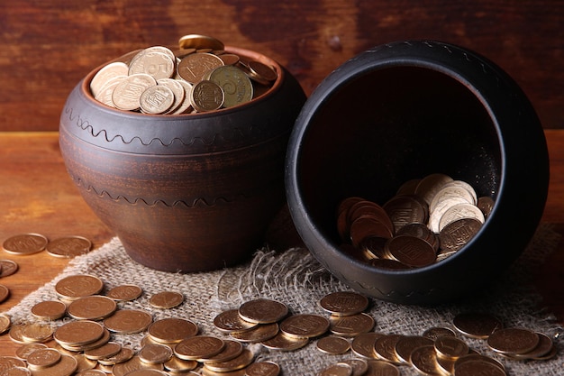 Golden coins in ceramic pots on wooden background