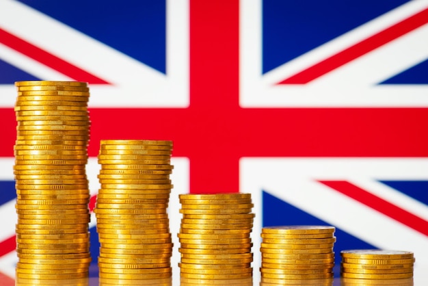 Golden coins in front of Great Britain flag Concept of economic recession of Great Britain