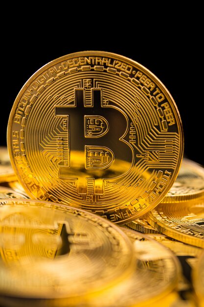 Golden coins with bitcoin symbol on a black background.