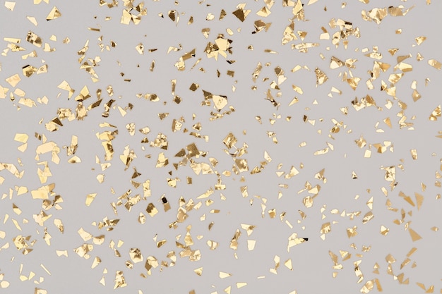 Golden confetti on grey background, party gold foil glitter backdrop.