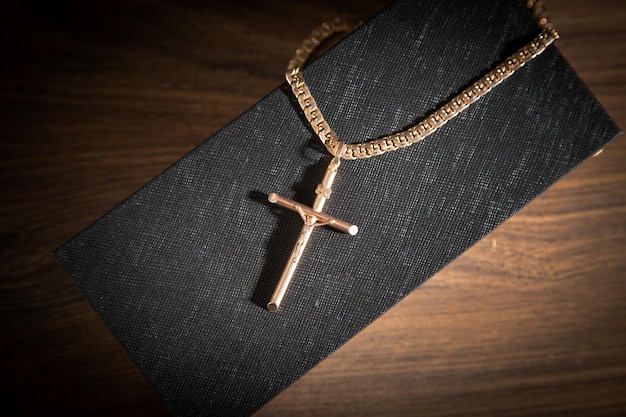 Golden cross necklace on wooden background