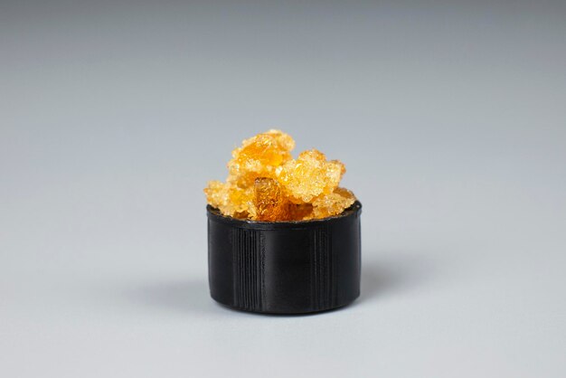 Golden crystals of cannabis wax glass container with crumbs of marijuana concentrate and copy space