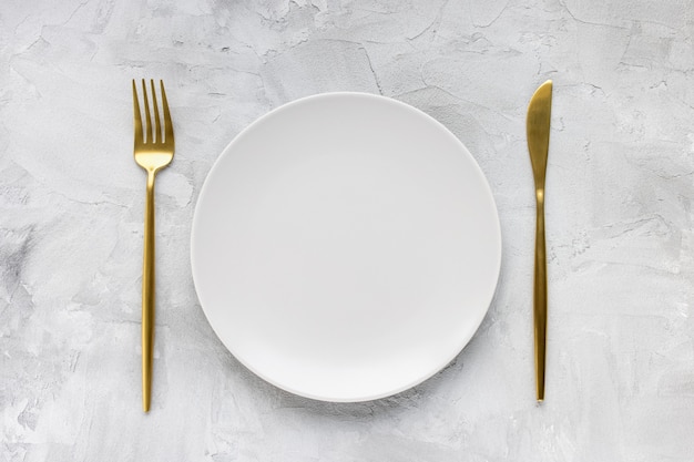 Golden cutlery and empty plate on gray table