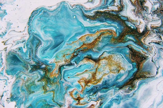 Photo golden and dark blue mixed acrylic paints marble texture liquid art