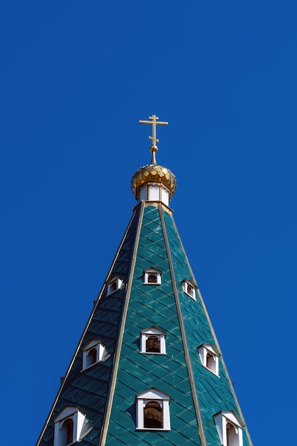 Golden dome with a cross on the green roof of aChurch