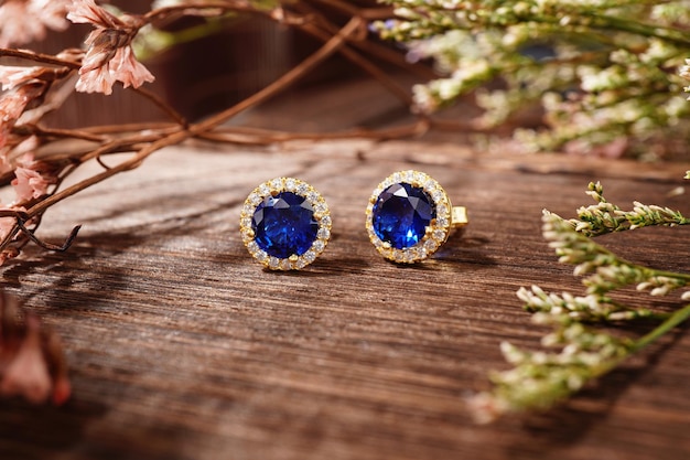 Golden earrings isolated, with blue crystals and diamonds. Beautiful earrings on wood background