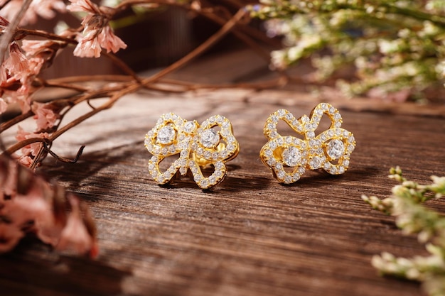 Golden earrings isolated, with white crystals and diamonds. Beautiful earrings on wood background