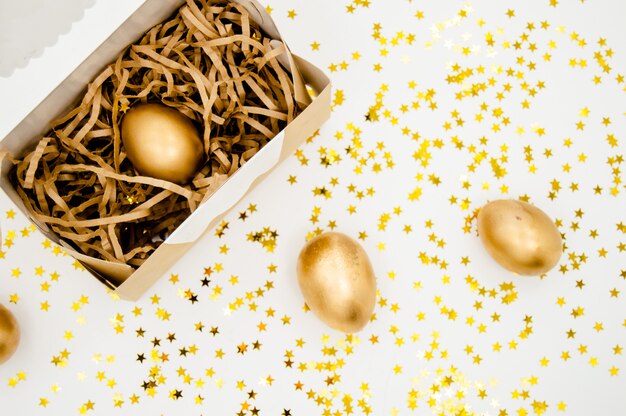 Uova di pasqua dorate in una scatola con le stelle dorate su fondo bianco